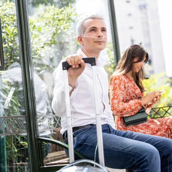 Aman waiting for bus with portable oxygen concentrator